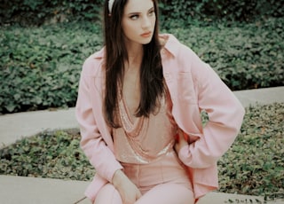 woman in pink blazer standing near green plant