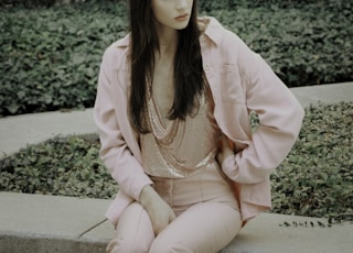 woman in pink blazer standing near green plant