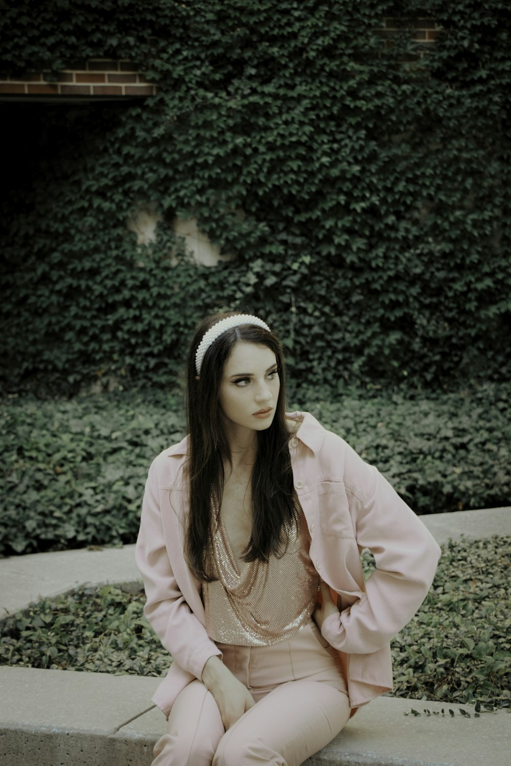 woman in pink blazer standing near green plant