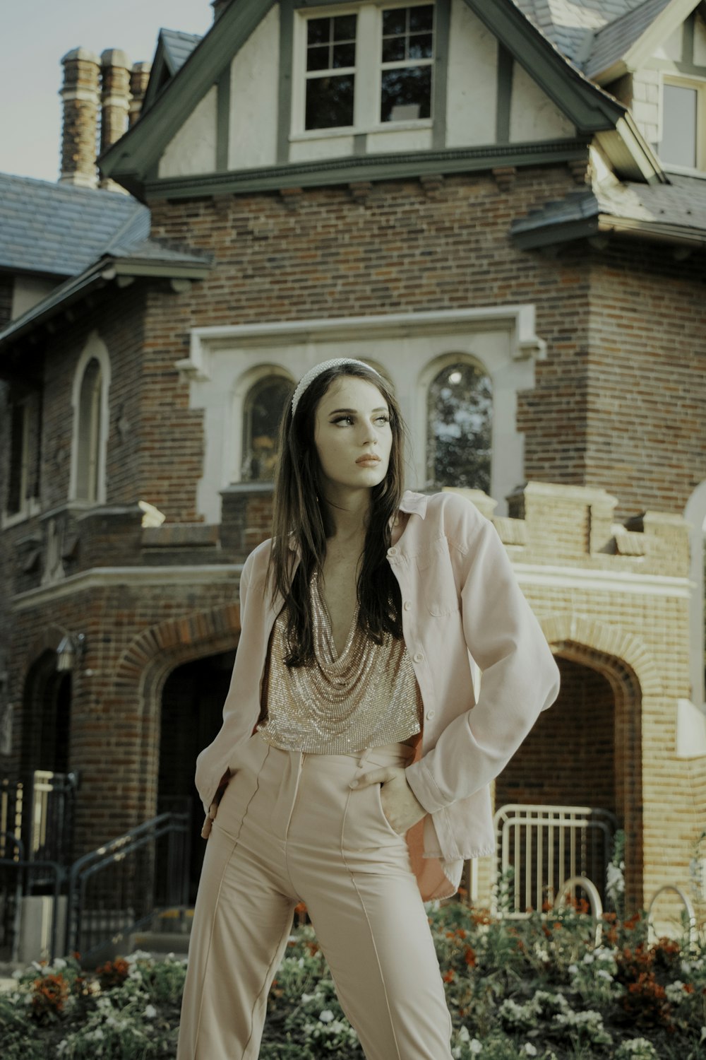 woman in pink long sleeve dress standing near brown brick building during daytime
