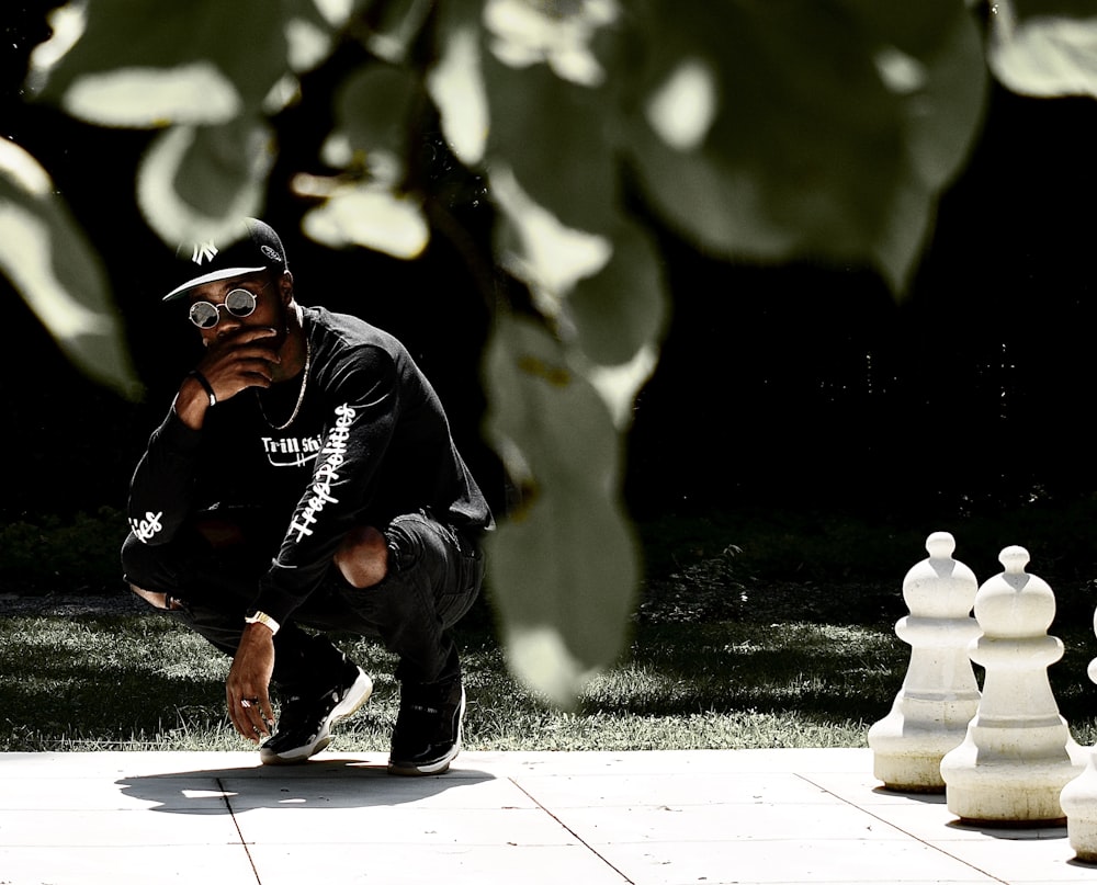 man in black jacket and black pants sitting on white concrete bench