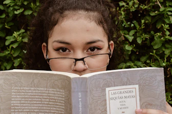 A young girl wearing glasses reading a book