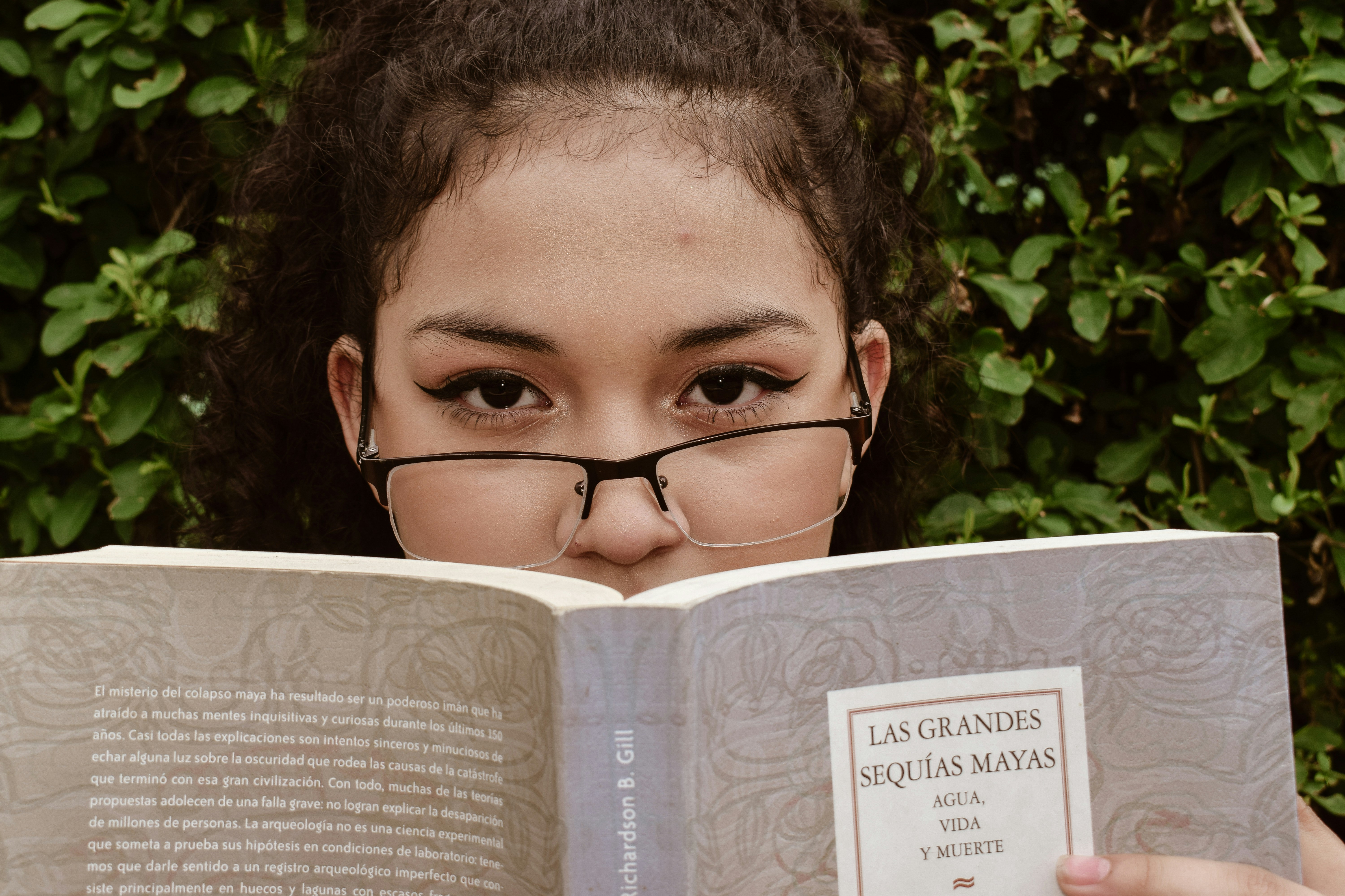 A young girl wearing glasses reading a book