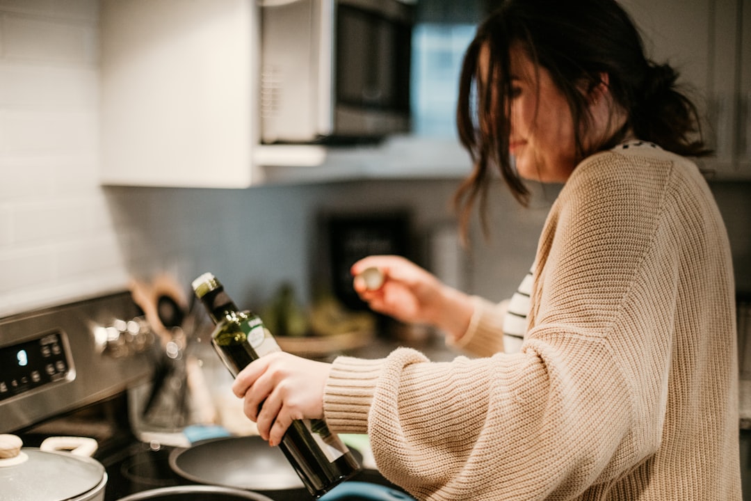 woman in white long sleeve shirt holding bottle