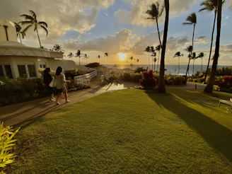 A serene Honolulu beachfront property at sunset, showcasing a well-maintained rental home with lush tropical landscaping.