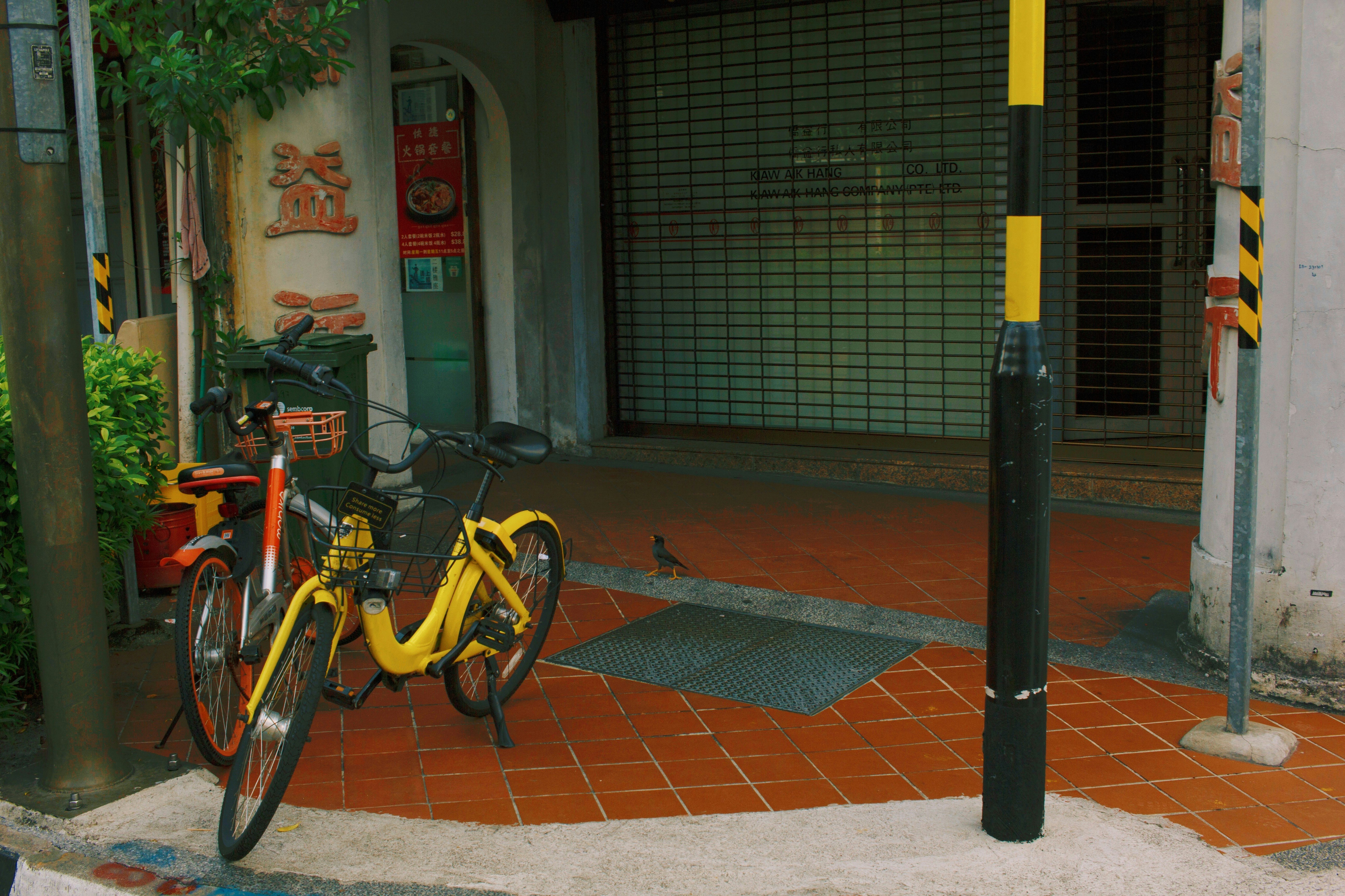 yellow and black bicycle parked beside black metal post
