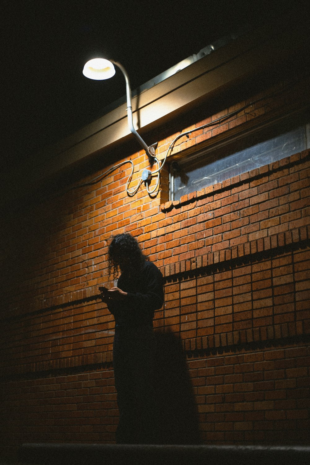 silhouette of person standing near brown brick wall