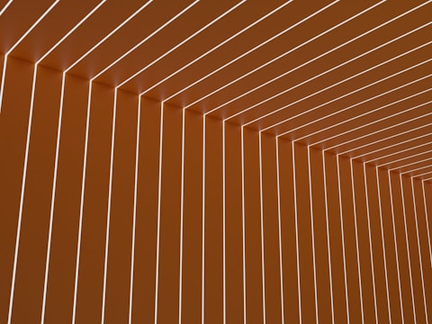 Uniform vertical and horizontal lines create a geometric pattern, forming an angular ceiling and wall design with an illusion of depth.