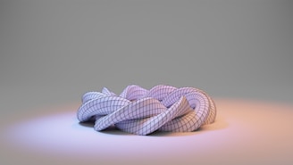A complex, three-dimensional geometric structure resembling a twisted or knotted shape sits on a gradient surface. The surface appears smooth and reflective, illuminated by soft bluish and orange lighting, highlighting the contours and grid pattern of the structure.