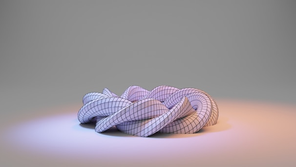 A complex, three-dimensional geometric structure resembling a twisted or knotted shape sits on a gradient surface. The surface appears smooth and reflective, illuminated by soft bluish and orange lighting, highlighting the contours and grid pattern of the structure.