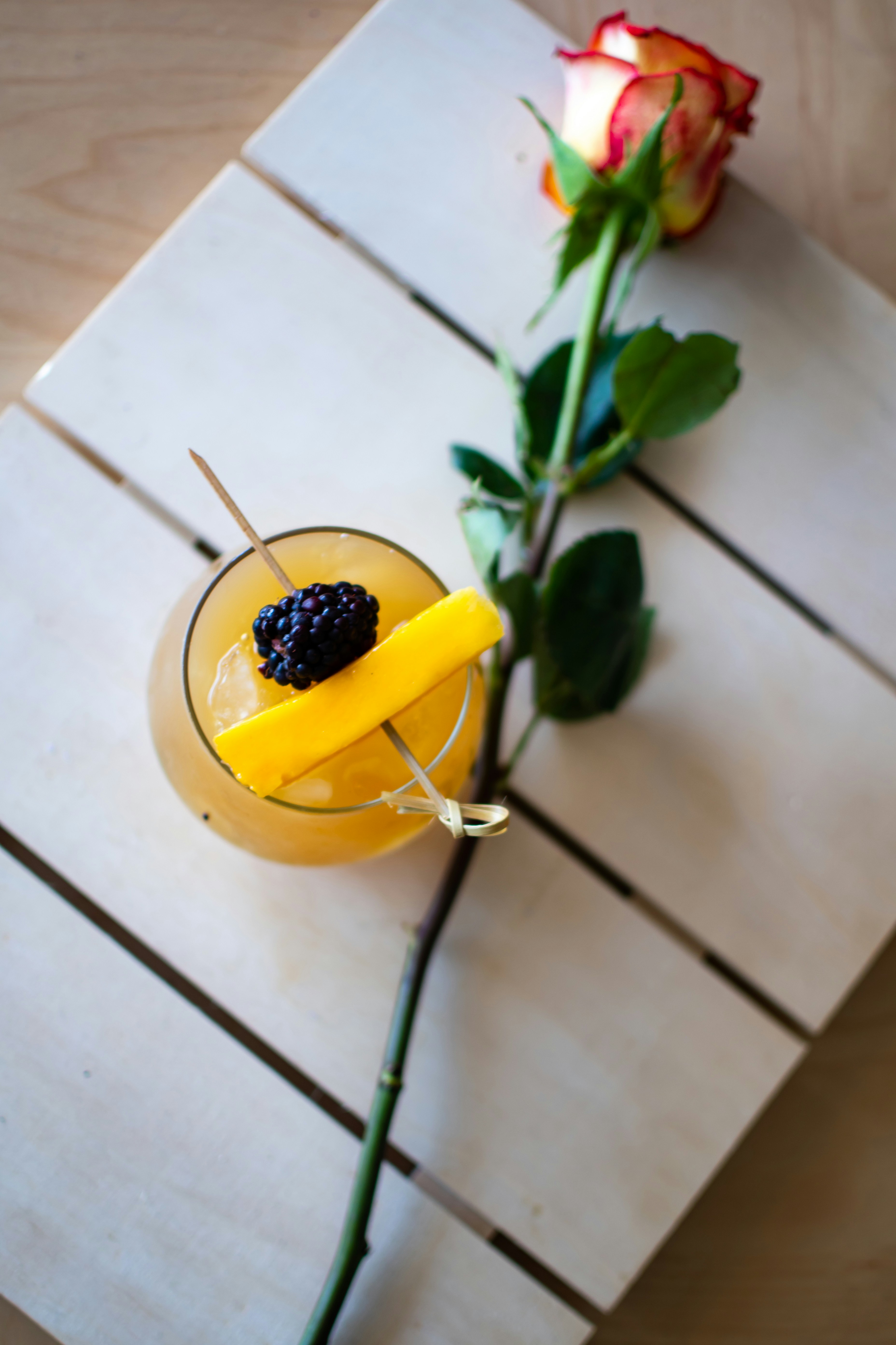 Tropical amber cocktail with chamoy rim and dried mango garnish, vibrant colorful background