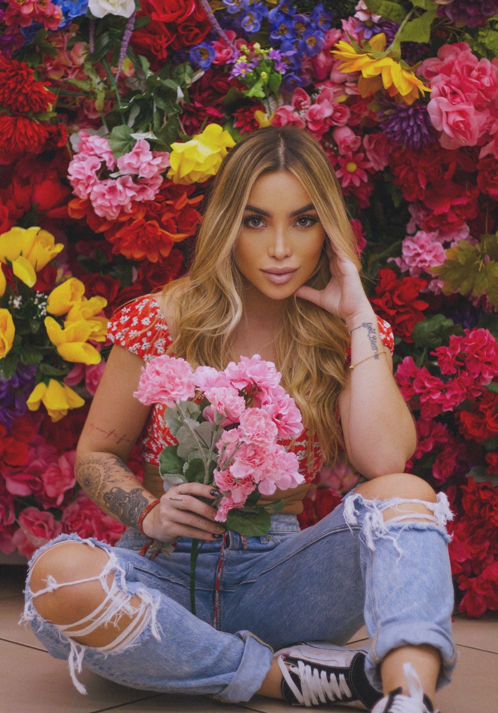 woman in blue denim shorts holding pink and yellow flowers