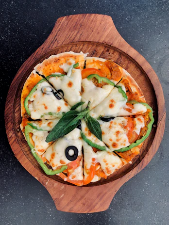 Close-up of a sizzling pepperoni pizza with melted cheese and fresh basil leaves on a wooden board
