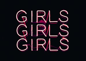 Neon pink lettering spells out the word 'GIRLS' three times in bold, stacked columns against a dark background.