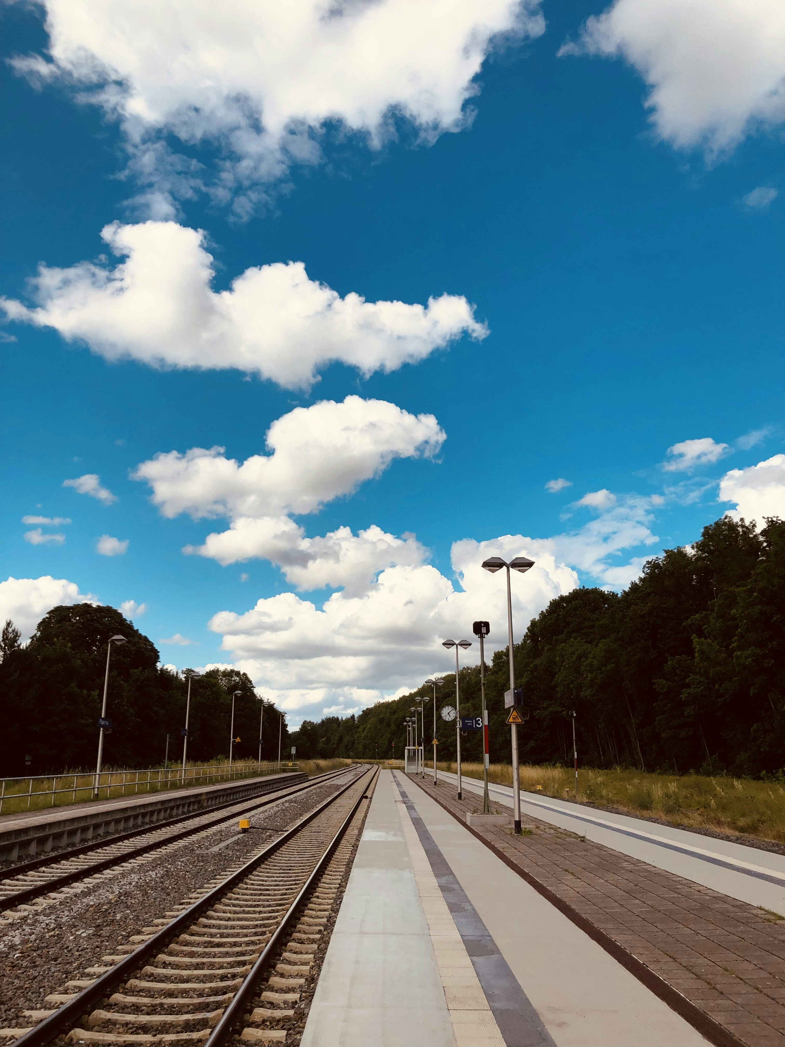 Graue Betonstraße unter blauem Himmel und weißen Wolken tagsüber