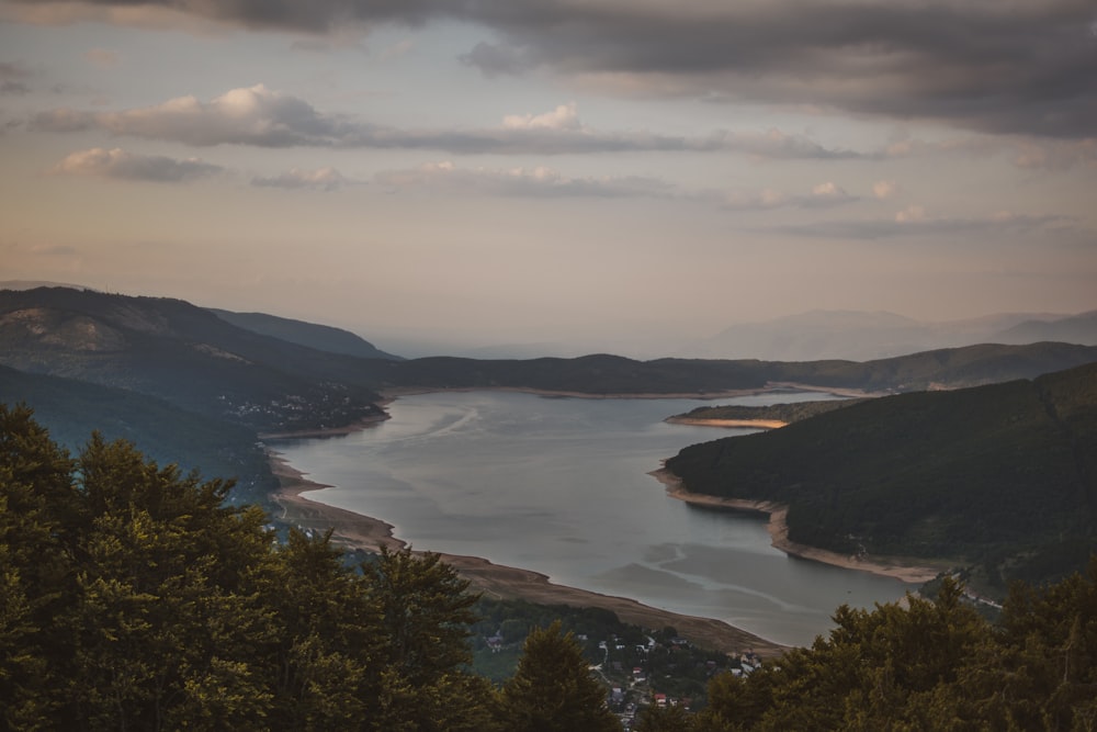 body of water between mountains under cloudy sky during daytime