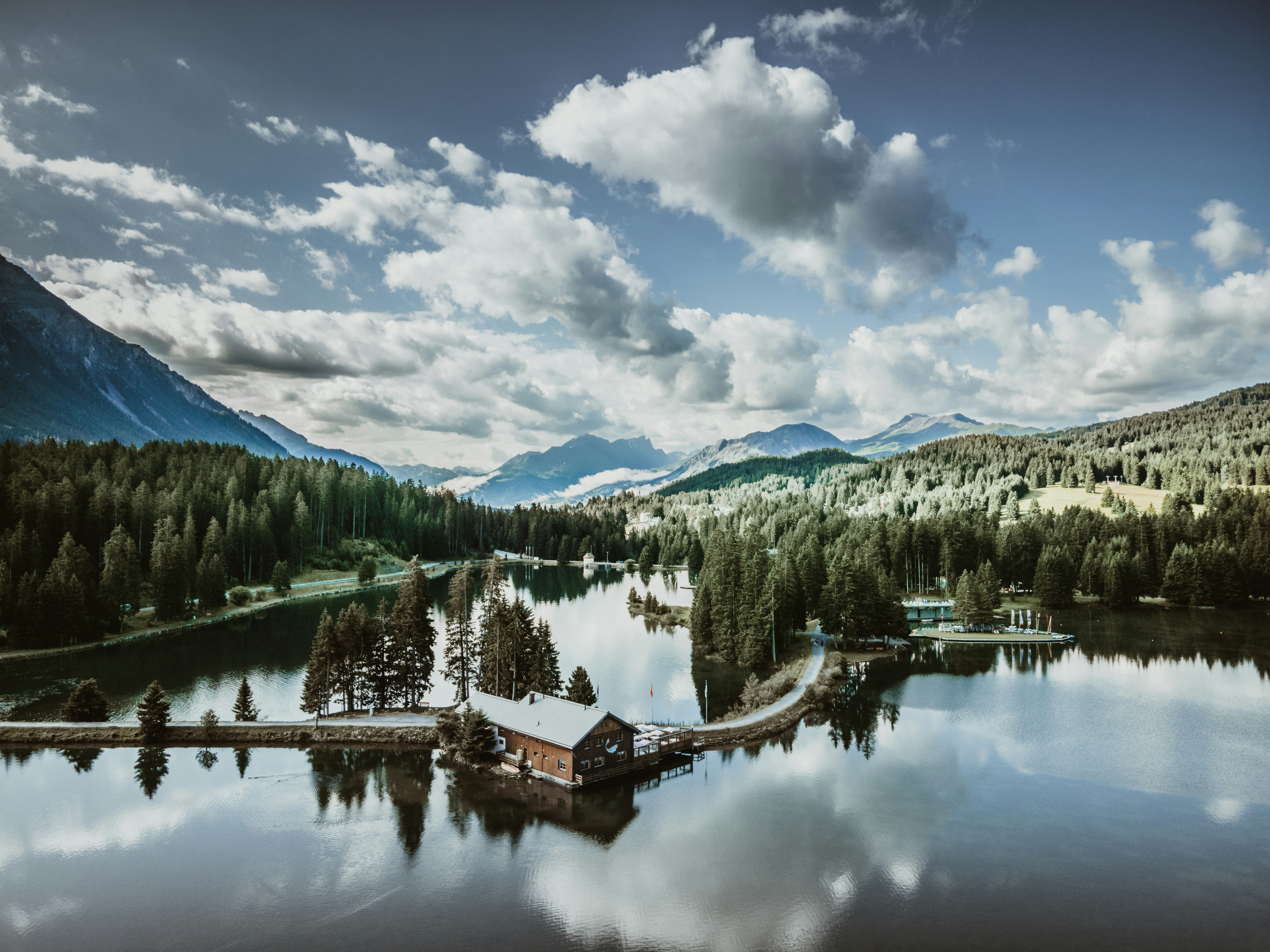 green pine trees near lake under blue sky and white clouds during daytime | Houfy — Book Direct