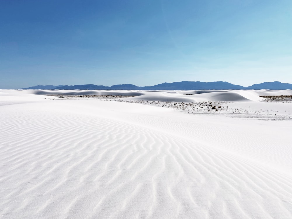 sable blanc sous le ciel bleu pendant la journée