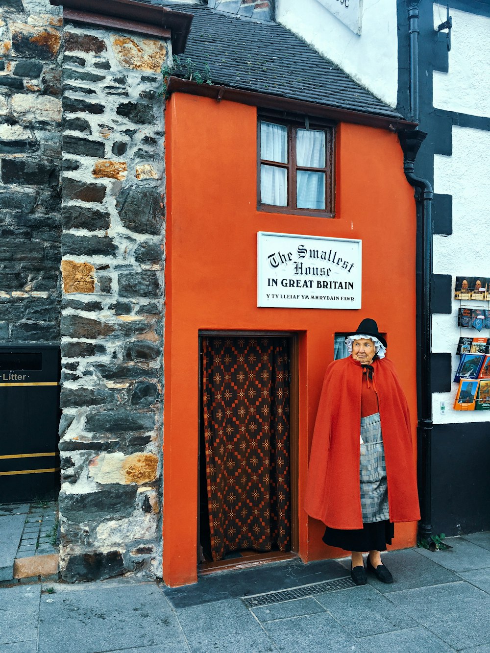 man in red robe standing in front of brown brick wall