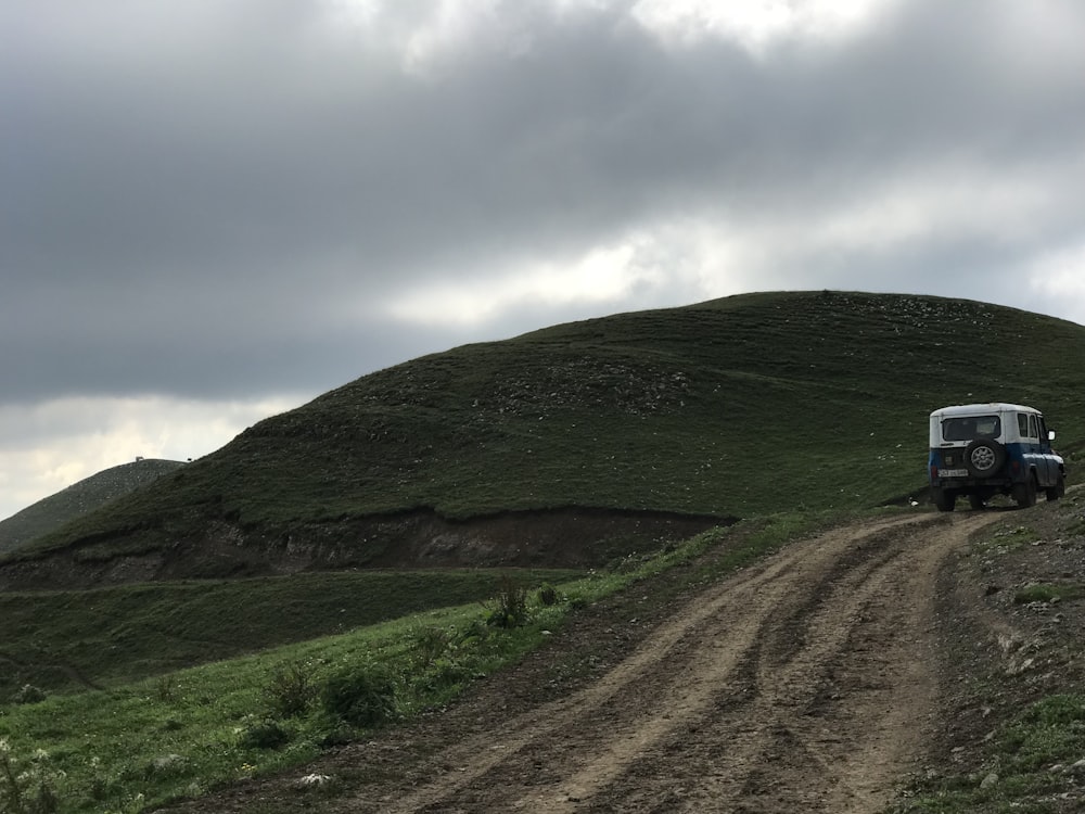 campo de hierba verde en la colina bajo las nubes blancas durante el día