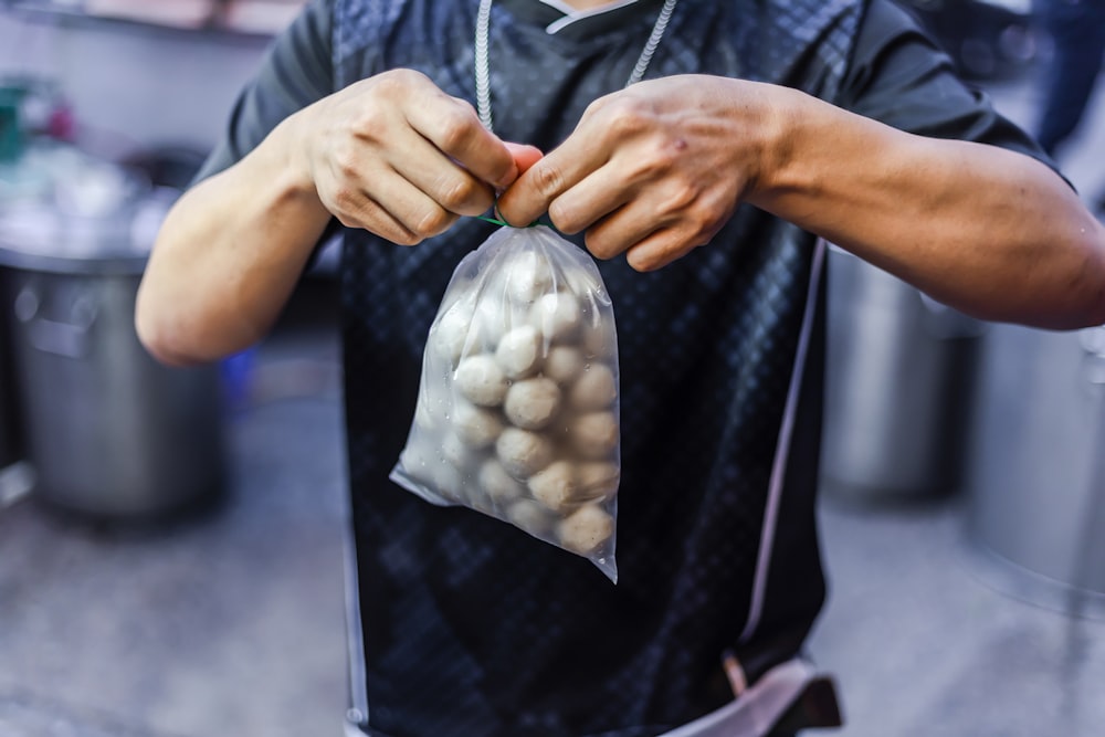 person in black button up shirt holding white and gray textile