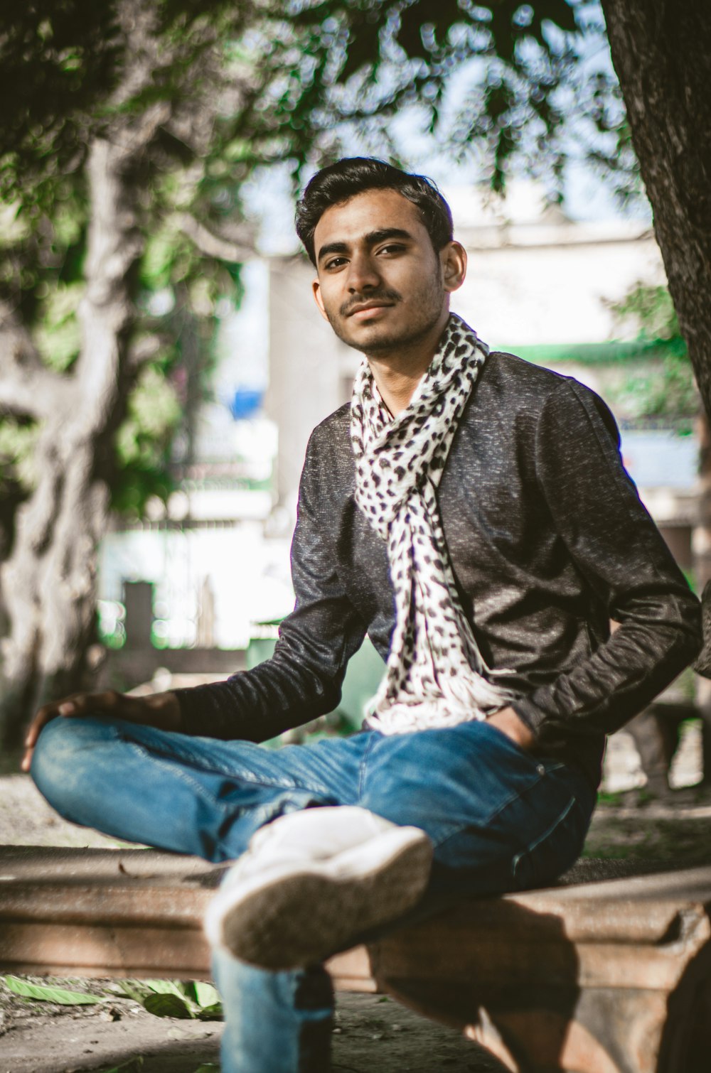 man in black blazer and blue denim jeans sitting on concrete bench