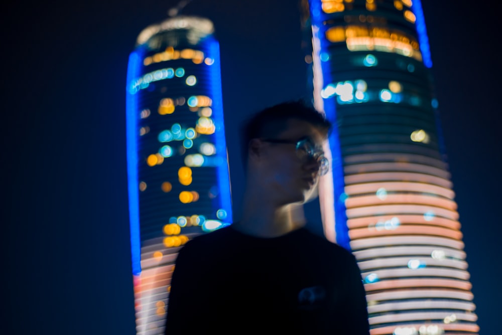 man in black crew neck shirt standing near blue and yellow lights