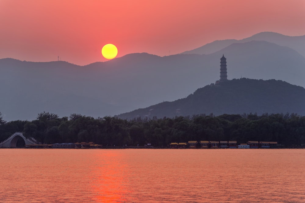 silhouette of mountain near body of water during sunset