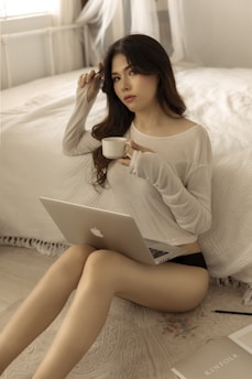 woman in white sweater sitting on bed