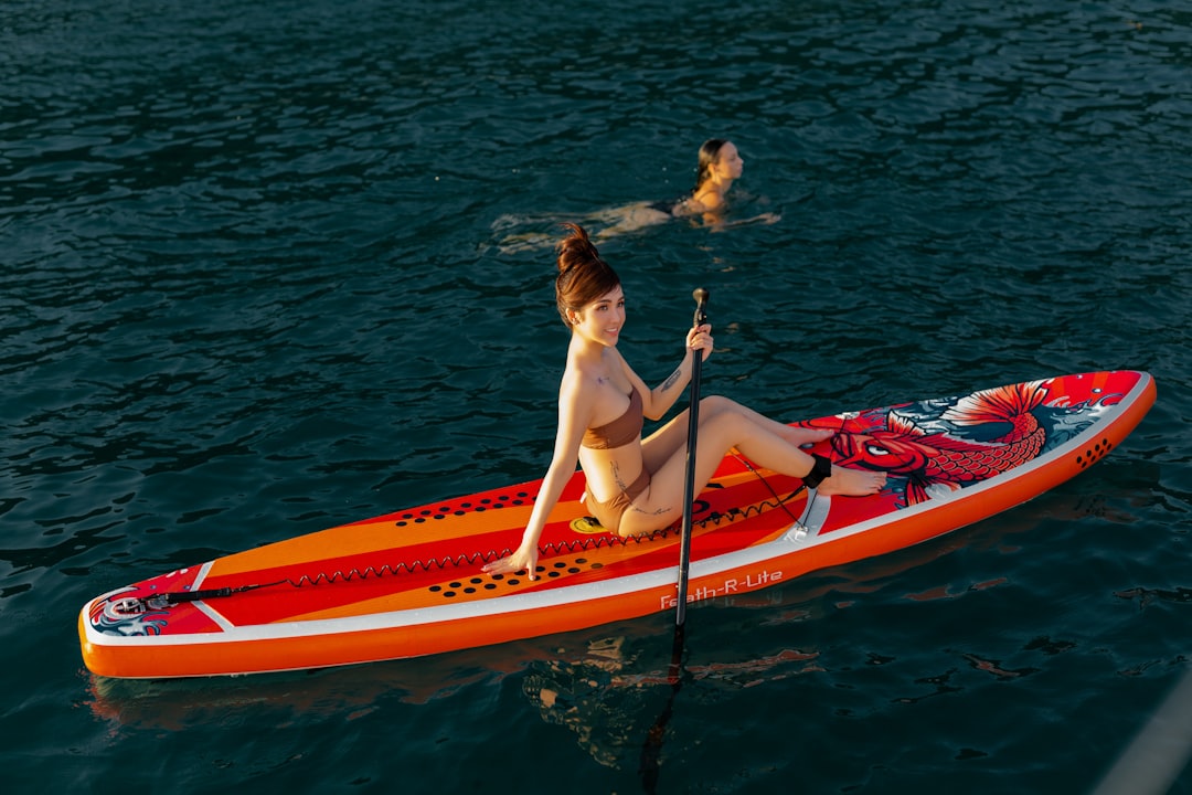 woman in blue bikini sitting on red kayak on body of water during daytime