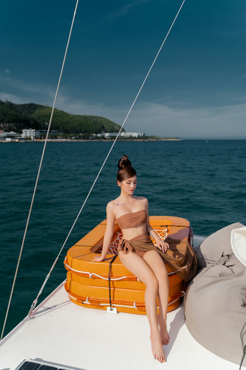 woman in orange bikini sitting on white and orange inflatable boat during daytime