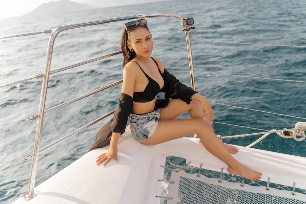 woman in black brassiere and blue denim shorts sitting on white boat during daytime