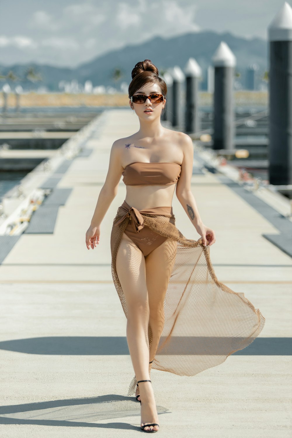 woman in yellow bikini sitting on white and brown striped hammock