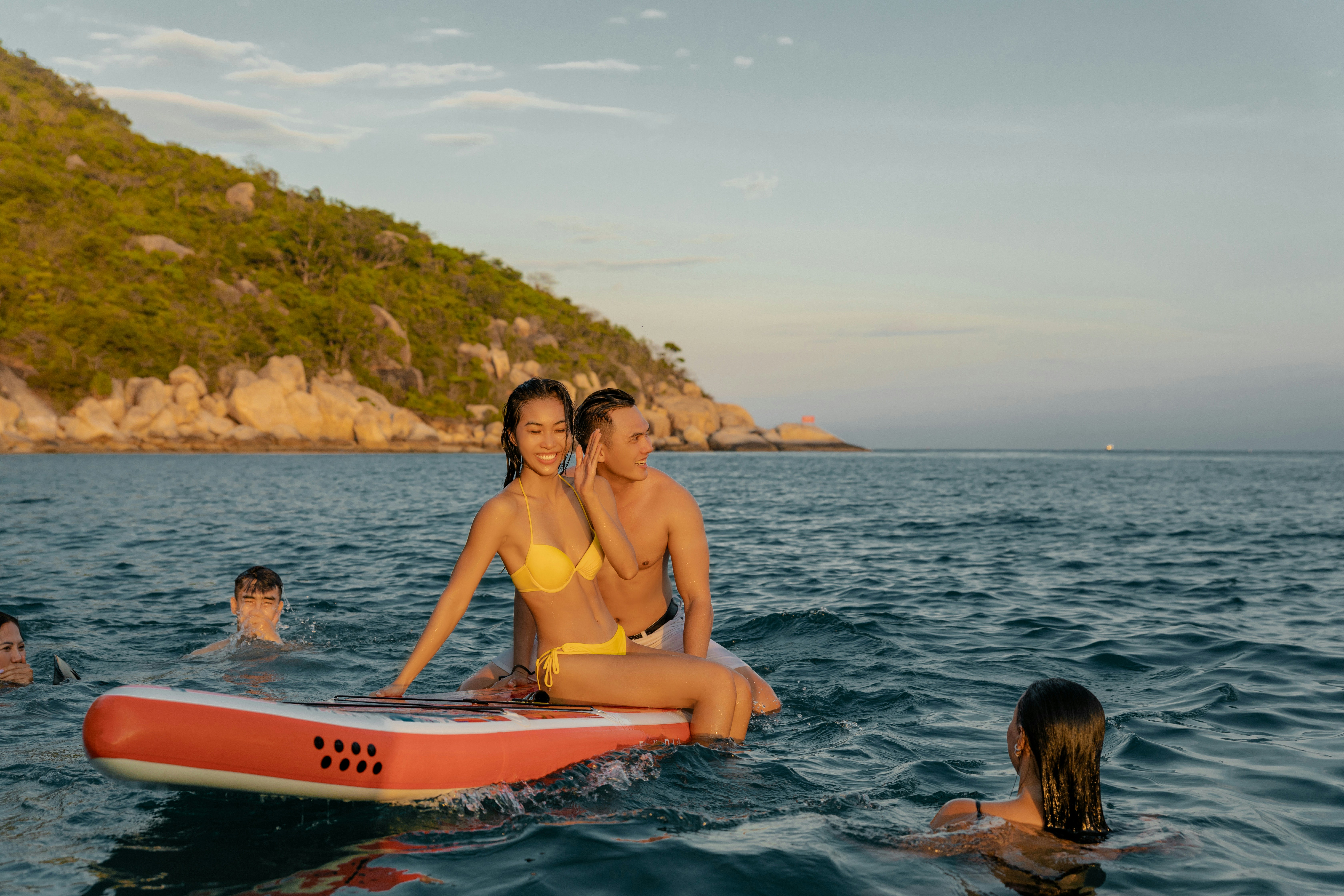 woman in pink bikini top riding on white and red surfboard during daytime
