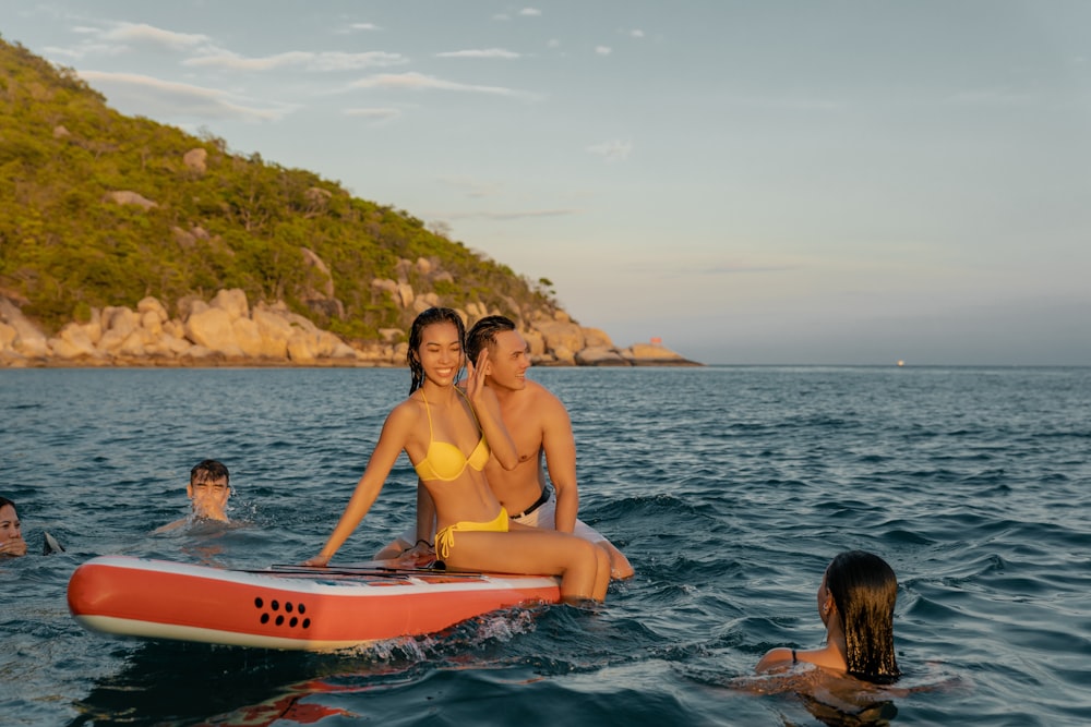 woman in pink bikini top riding on white and red surfboard during daytime