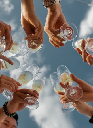 people holding clear glass bottles during daytime