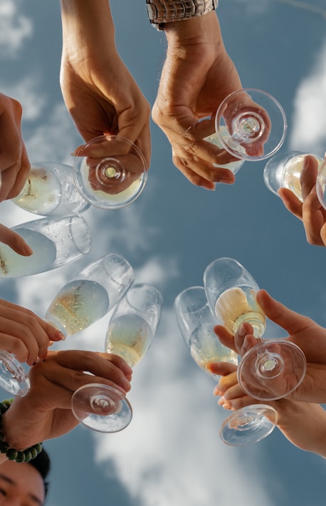 people holding clear glass bottles during daytime