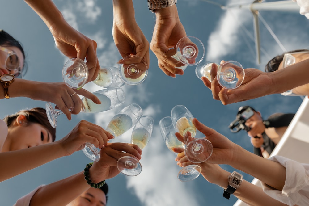 people holding clear glass bottles during daytime