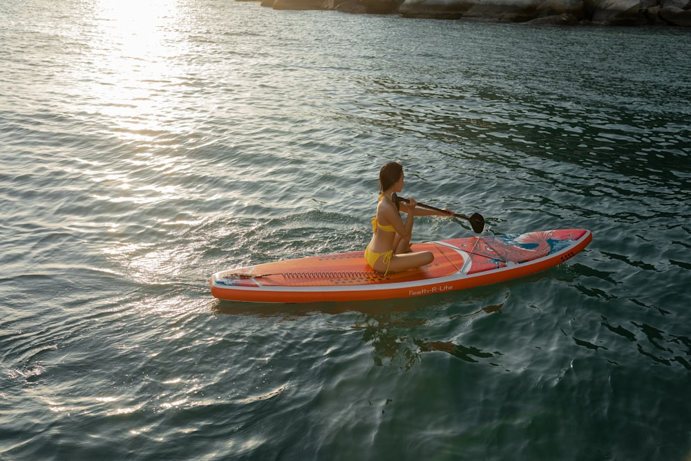 man in red shirt riding orange kayak on body of water during daytime