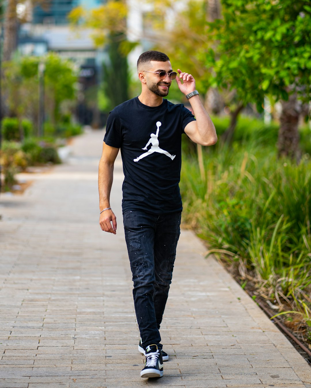 man in black crew neck t-shirt and black pants standing on sidewalk during daytime