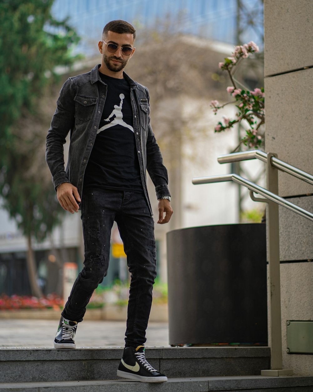 Homme en veste en cuir noir et jean bleu debout à côté d'un mur de béton  gris pendant la journée photo – Photo Tel Aviv Gratuite sur Unsplash