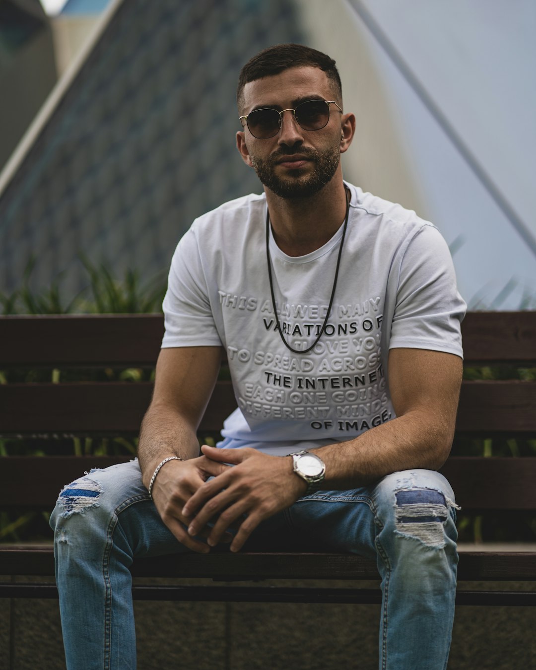 man in white crew neck t-shirt and blue denim jeans sitting on brown wooden bench