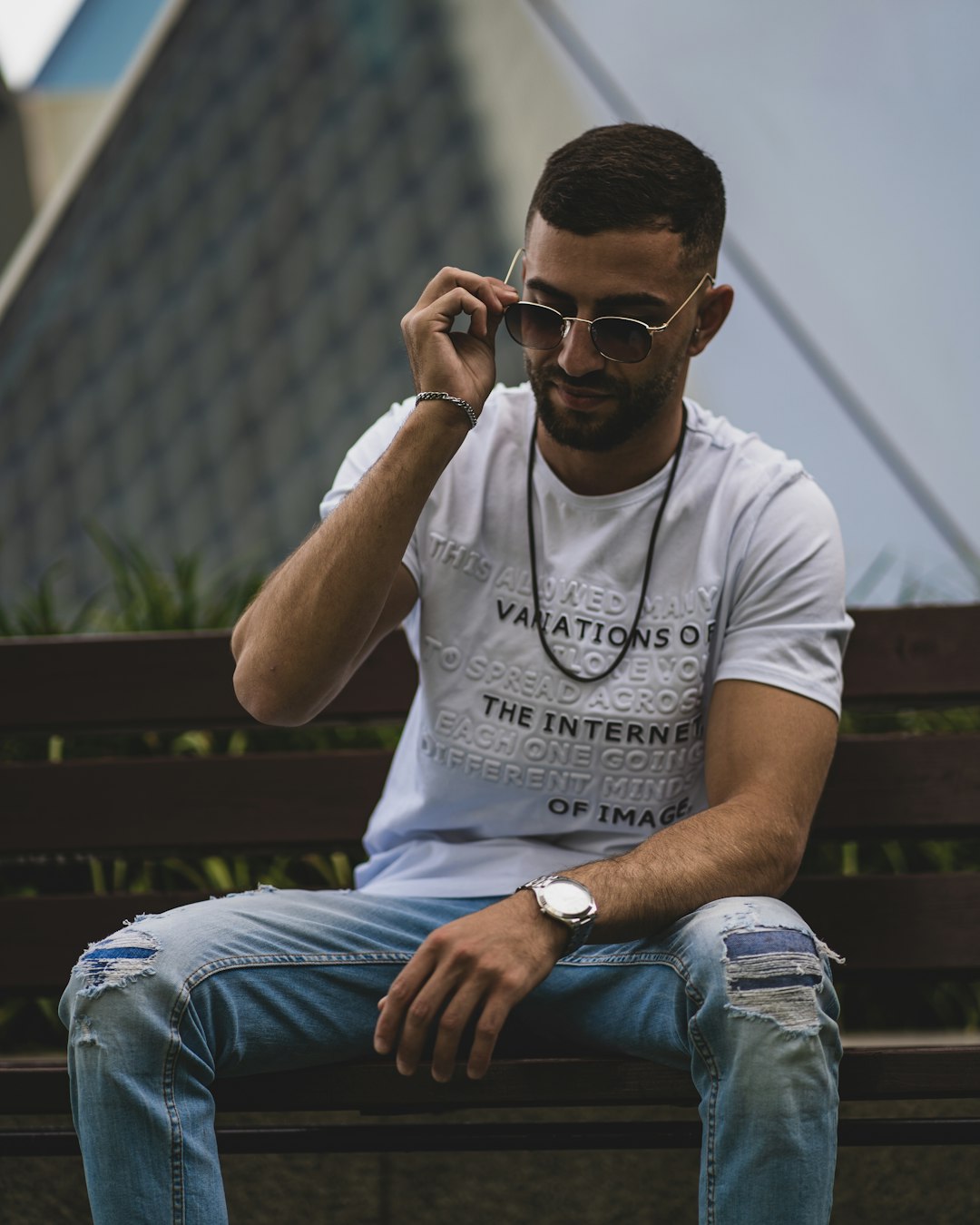 man in white crew neck t-shirt and blue denim jeans wearing black sunglasses sitting on on on on sitting