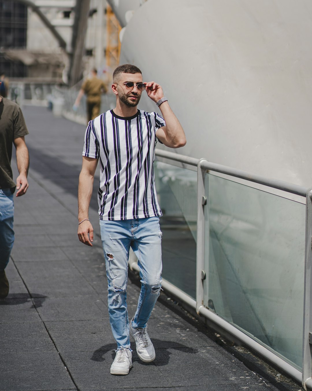 man in white and black striped crew neck t-shirt and blue denim jeans standing on with with with with