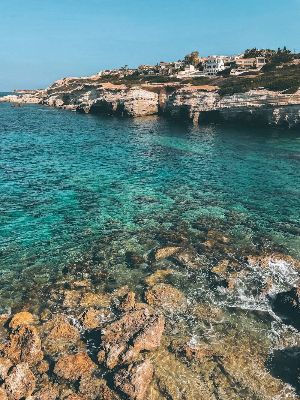 brown rocky shore with blue water during daytime