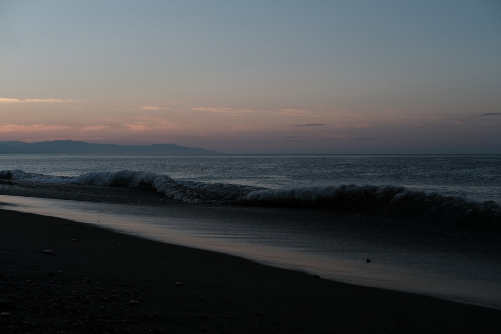 sea waves crashing on shore during sunset