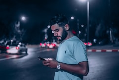 man in white polo shirt holding smartphone