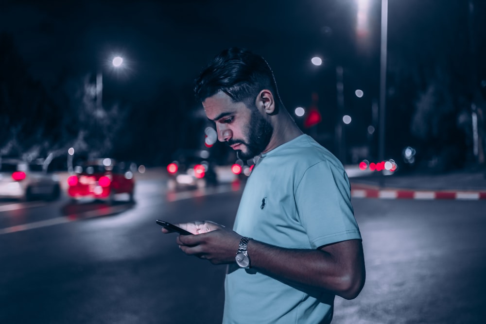 hombre con polo blanco sosteniendo un teléfono inteligente