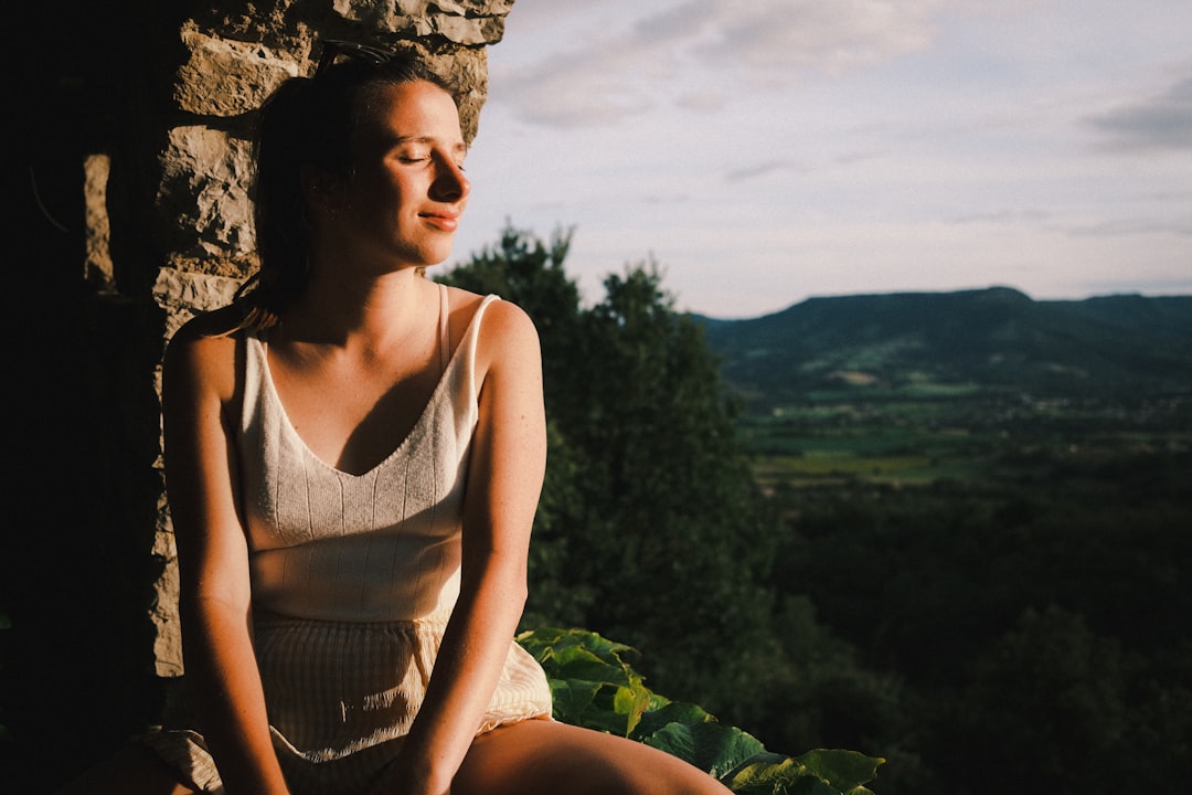 woman in white tank top sitting on rock