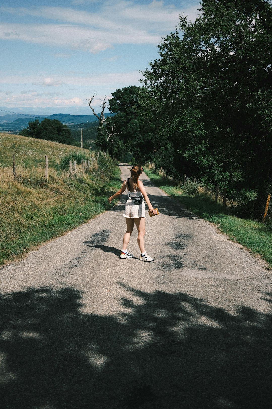 woman in white dress walking on road during daytime